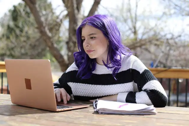 Estudiante con el oído morado llevando un jersey a rayas mirando su portátil